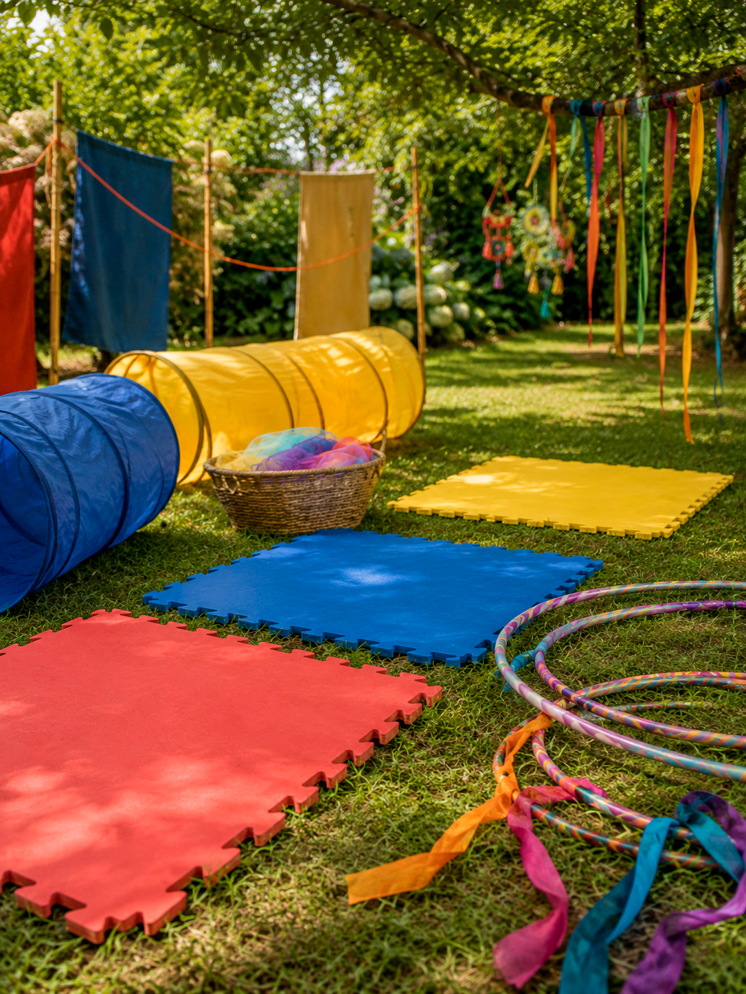 Imagem conceitual de um circuito infantil ao ar livre com túneis coloridos, tapetes de EVA e bambolês sobre um gramado.